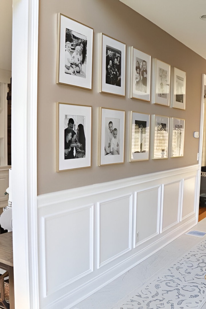 Gallery wall in Indore featuring framed black and white photos, white wainscoting, and neutral wall paint.