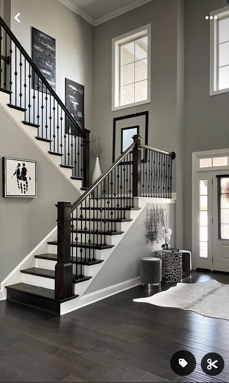 Modern elegant entryway and staircase in Indore featuring dark wood steps, black metal spindles, and neutral walls.