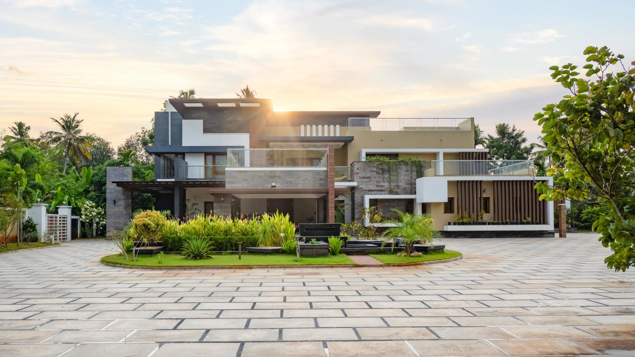 Modern luxury villa exterior in Indore featuring a contemporary multi-level facade, stone cladding, and paved driveway.