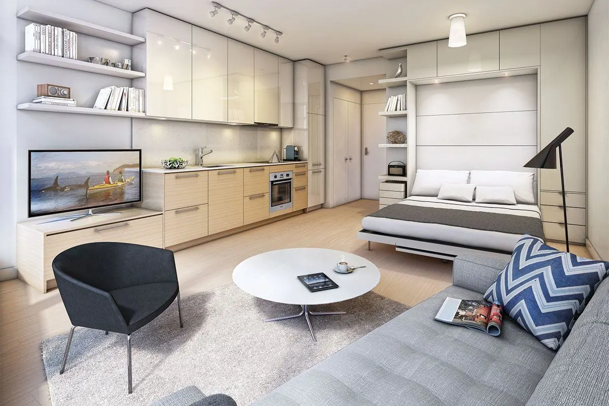 Modern studio apartment interior in Indore featuring a wall bed, integrated kitchen, living area, and smart storage.