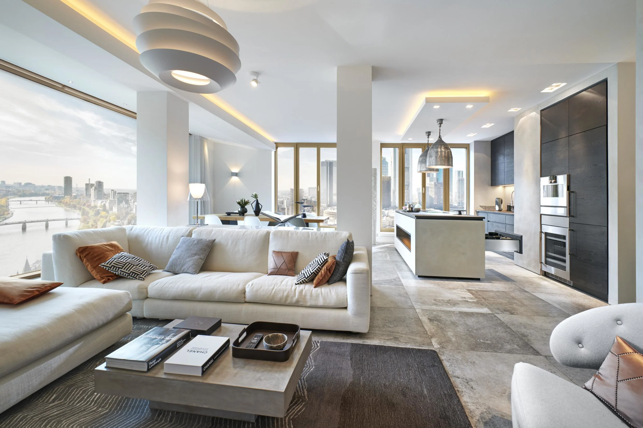 Modern luxury apartment interior in Indore featuring a white sectional sofa, open-concept kitchen, and expansive city views.